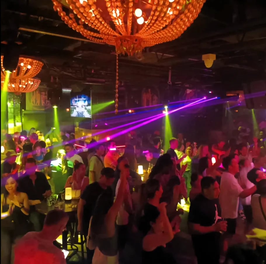 Crowded Taboo nightclub with purple and green neon lights, glowing decorative spheres, and people dancing on the dance floor